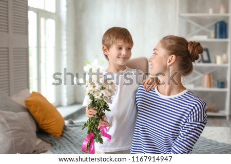 Mother receiving flowers from her cute little son at home