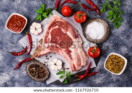 Raw meat with bones on a dark background with spices. Selective focus.
