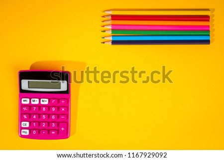 yellow school background with a crayons, calculator, ruler and felt-tip pens