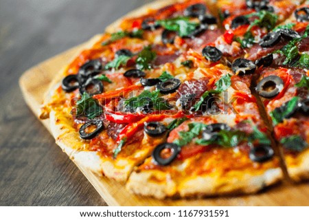 slices of Pizza with Mozzarella cheese, salami, pepper, pepperoni, Tomatoes, olives, Spices and Fresh Basil. Italian pizza on wooden background