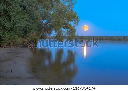 Full red moon in the sky over the Volga River opposite village of Emmaus, near town of Tver, Russia.