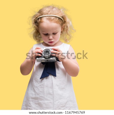 Beautiful blonde toddler taking pictures with vintage camera