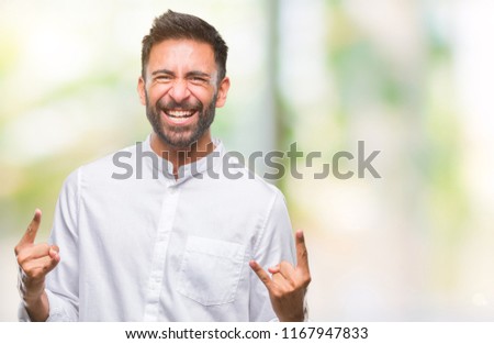Adult hispanic man over isolated background shouting with crazy expression doing rock symbol with hands up. Music star. Heavy concept.
