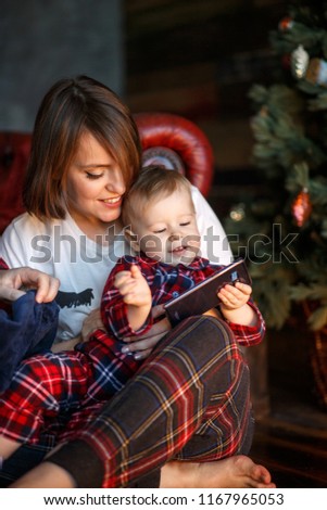 Picture of parents sitting together with their child on the floor. They are looking at him. Kid is playing on th phone. Dad is holding child on nap.