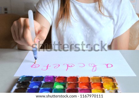 Teenager girl lettering alphabet with colorful paints palette on front