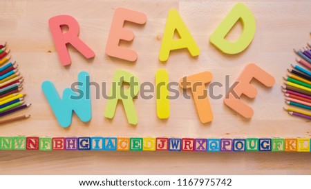 Words READ and WRITE from multicolor wooden letters on wooden table.