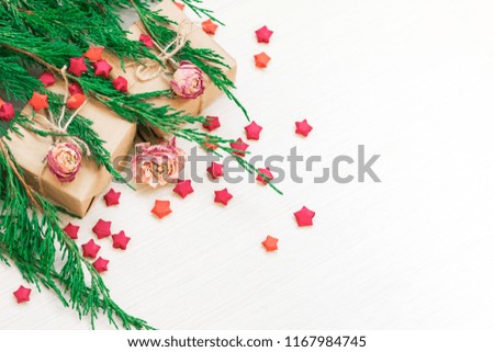 Christmas composition. Gifts, red paper stars, flowers, pine branches against a white tree background. Top view, layout
