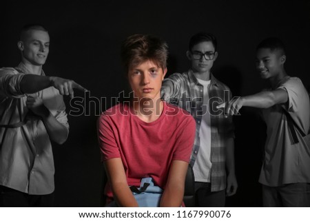 Teenagers bullying boy on dark background Royalty-Free Stock Photo #1167990076