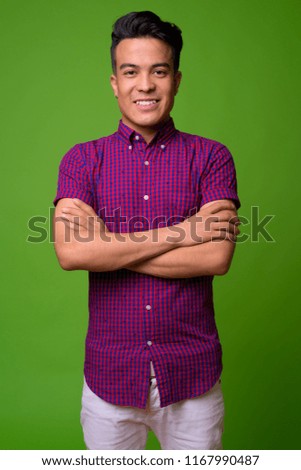 Young multi-ethnic man wearing purple shirt against green background