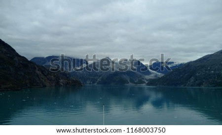 Glacier running through snow covered peaks reflecting off the water off the pacific ocean. Beautifully serene picture