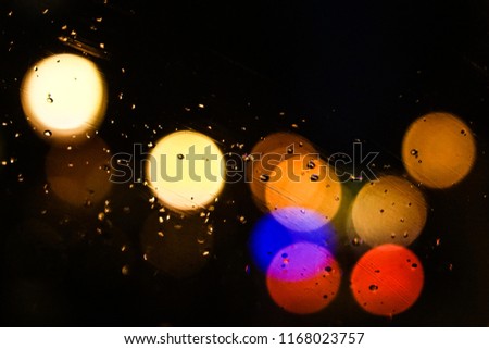 Artistic closeup macro through a car windshield of bokeh colorful street lights at night, like a pattern, with rain texture, creating a fairy jazzy and romantic atmosphere, Paris city, France.