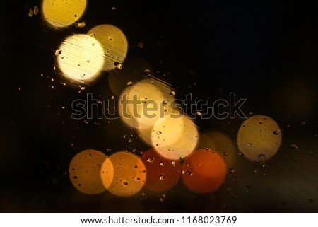 Artistic closeup macro through a car windshield of bokeh colorful street lights at night, like a pattern, with rain texture, creating a fairy jazzy and romantic atmosphere, Paris city, France.