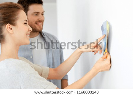 repair, people and interior design concept - happy couple with color samples palettes at new home