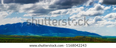 Panoramic view of Wyoming's ominous cloudy skies over open fields and sections of the Laramie Mountain Range, seen from highway 80 