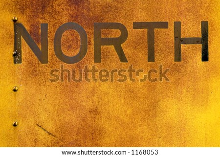 The word North is old and faded and painted on the side of a old train car.