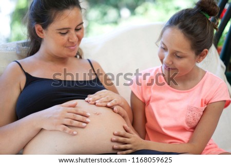 pregnant, happy mother, together with her daughter while waiting for her baby