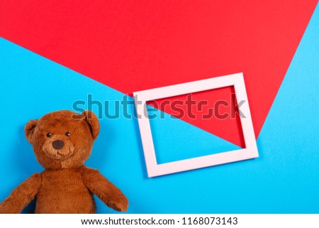 Teddy bear and white empty frame on colorful background