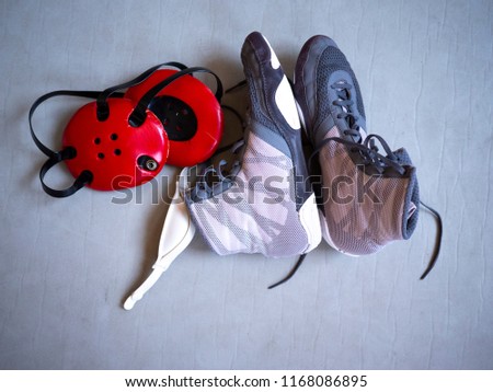 Wrestling shoes and headgear on a grey mat