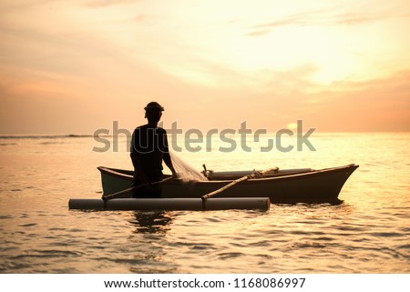 silheoutte of fisherman with boat during sunrise. selective focus.