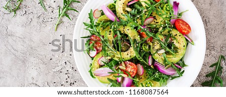 Diet menu. Healthy salad of fresh vegetables - tomatoes, avocado, arugula, radish and seeds on a bowl. Vegan food. Flat lay. Banner. Top view Royalty-Free Stock Photo #1168087564