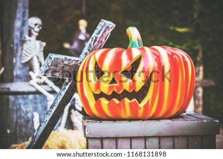 Halloween pumpkin in Graveyard, Skeleton with crosses in Spooky Land, selective focus, vintage toned