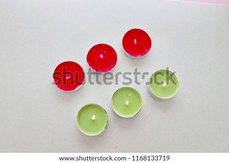 Red and lime green tea light candles in a row on a plain background.wick for lighting