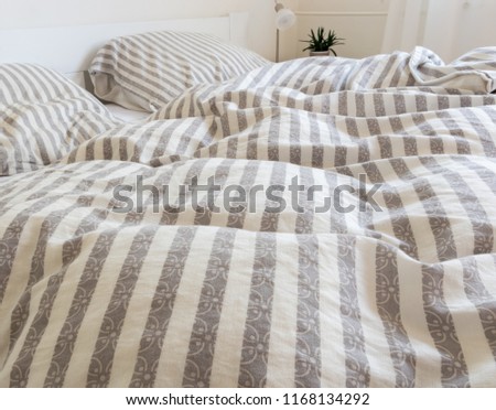 striped bedclothes on bed, and untouched duvets and pillows in the morning, long night sleep