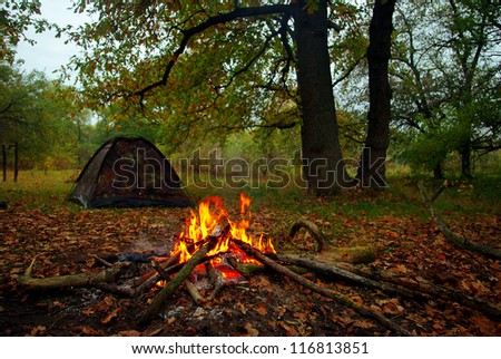 Camp fire and tourist tent in the background