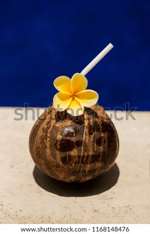 Coconut drink with yellow flower at poolside.