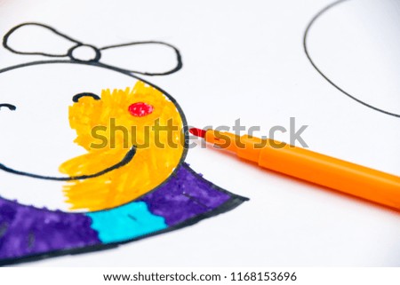 Girl draws a picture of a girl with a felt-tip pen