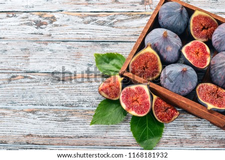 Figs in a wooden box on a white wooden background. Free space for text. Top view.