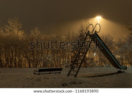 Empty playground covered in snow at night