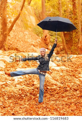 Picture of sweet girl jumping with umbrella in autumnal park