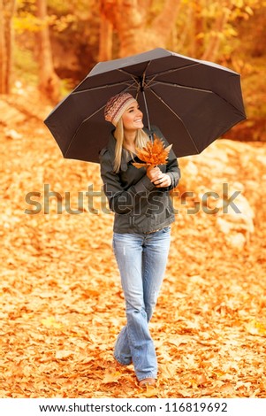 Picture of pretty woman standing under umbrella in fall forest in rainy weather