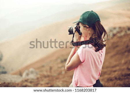 Photographer shooting landscape. Trendy woman tourist traveler with the photo camera on the mountains. In the hands of the camera.
