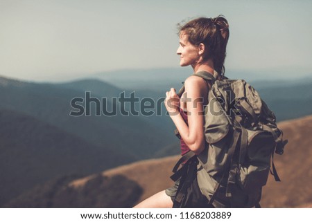 A young female tourist with a tourist backpack looks at a beautiful landscape. Background valley landscape view mockup for text. Vintage photo. Experienced tourist.