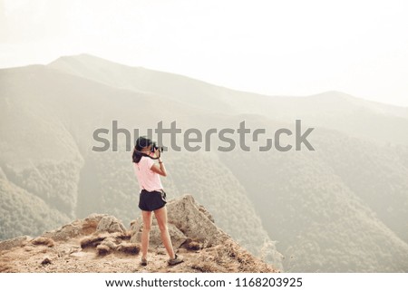 Woman taking pictures of mountain landscape. Trendy girl with the camera on the mountains. Nature girl. Background valley landscape view mockup for text.
