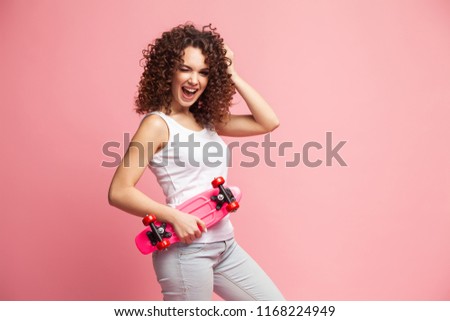 Portrait of funny hipster girl with pink longboard over pink background