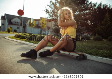 Shot of a handsome young blonde on the street sitting on the longboard