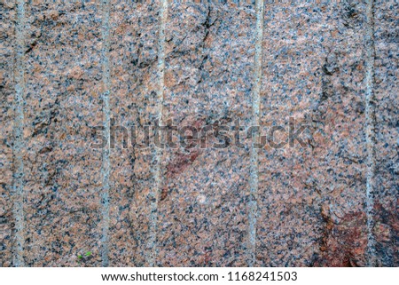 Abstract background. Close-up view of natural rought untreated granite texture, red base with black and gray spots.