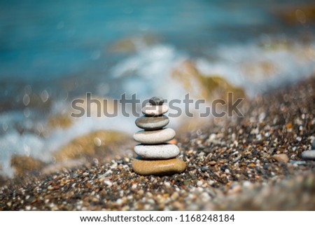 Pyramid of pebble stone on the beach on the background of the sea. Selective soft focus, shallow depth of field. Blurred back and foreground.