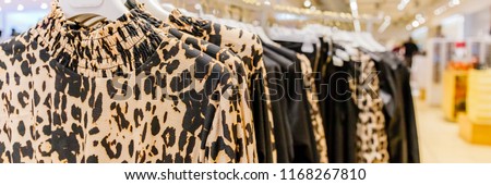 Women's blouses with classic animal print hang on hangers, banner background