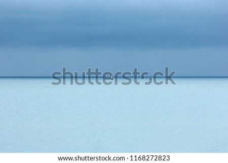 Small white yacht, turquoise blue sea and dark blue sky with clouds, a rainy day