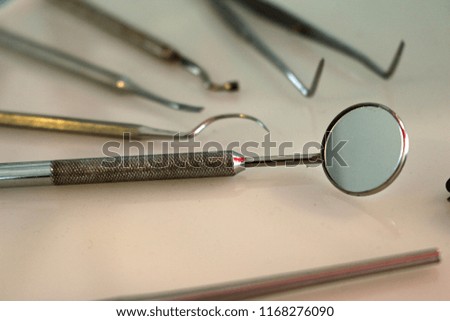 Various dental tools from the mid 1900s with the focus on a mouth mirror with other tools blurred into the background.