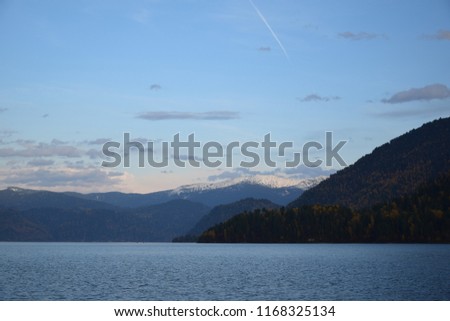 
The shore of Teletskoye lake in the evening, before sunset, in the background autumn forest and mountain peaks with snow caps. The Republic of Gorny Altai. The picture was made in the autumn warm eve