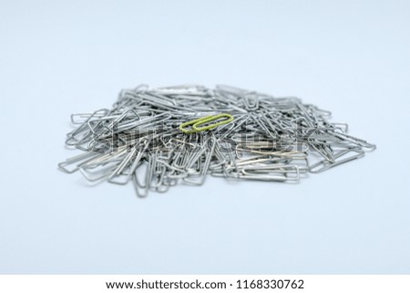 A yellow paper clip on the heap of silver paper clip isolated on white background.