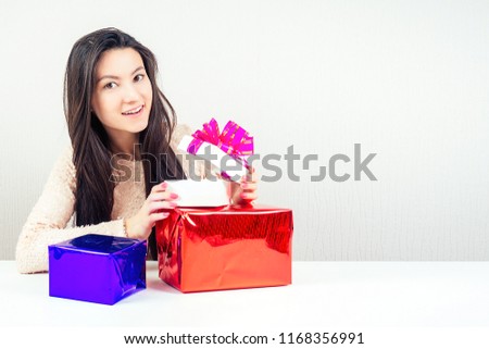 attractive brunette woman opens bright boxes with gifts. concept of a holiday and a surprise