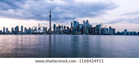Toronto, Ontario - Canada. Long exposure of wide panorama of Toronto, Ontario - Canada. Bright sky with a smooth water surface. Beautiful city lights seen from the Toronto Island.