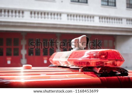 Close up on the red and white siren lights on a Fire Department vehicle, with firehouse  n the blurry background and space for text