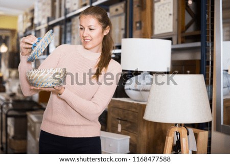 Positive woman buyer holding wicker basket in furniture shop